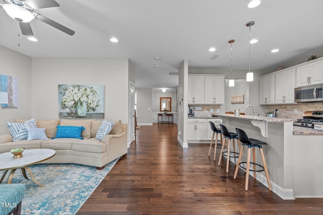 living area featuring dark wood finished floors, recessed lighting, baseboards, and ceiling fan