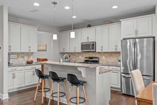 kitchen with stainless steel appliances, dark wood finished floors, an island with sink, backsplash, and white cabinets