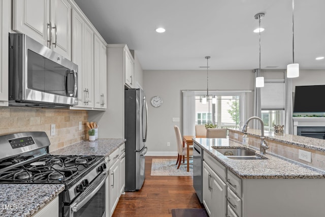 kitchen with stainless steel appliances, a sink, dark wood-style floors, backsplash, and recessed lighting