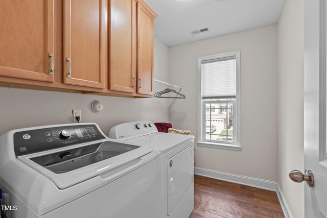 laundry room with washing machine and clothes dryer, wood finished floors, baseboards, and cabinet space