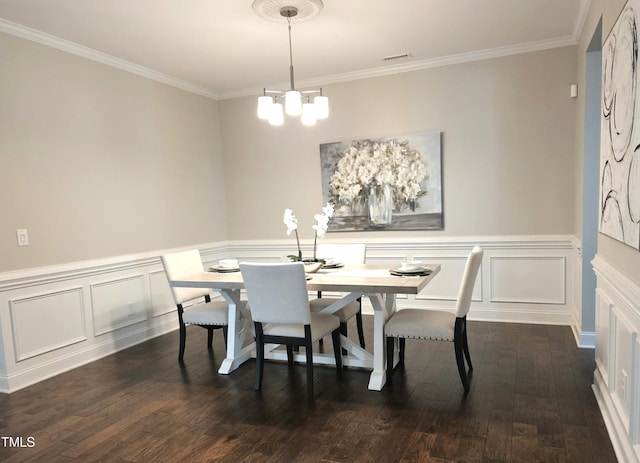 dining room with dark wood finished floors, crown molding, a chandelier, a wainscoted wall, and a decorative wall