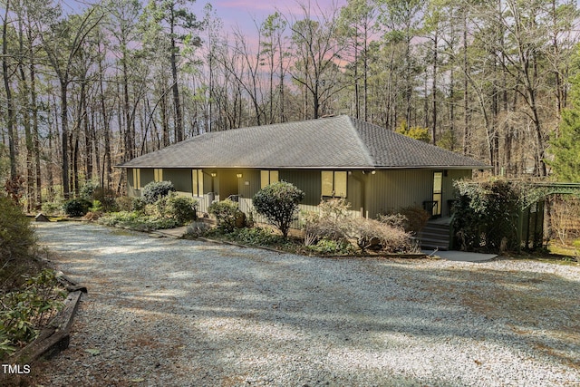 view of front of house with gravel driveway and a wooded view