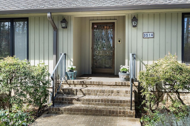 view of exterior entry featuring roof with shingles