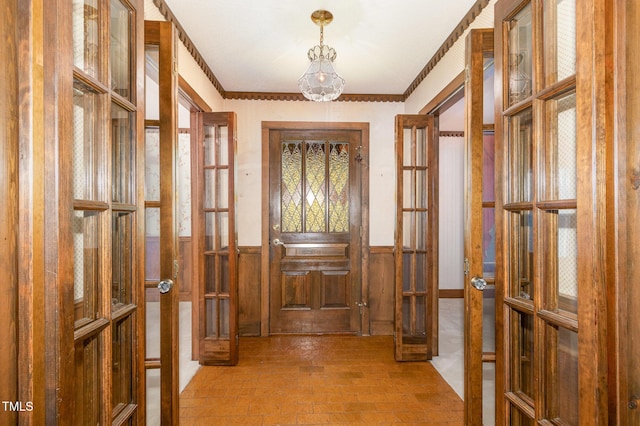 entryway featuring french doors, crown molding, and wainscoting