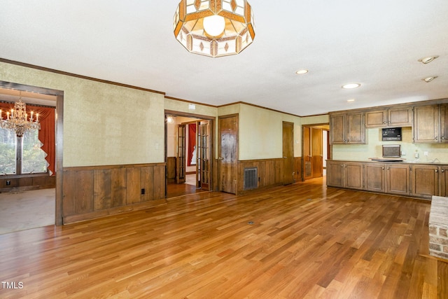 kitchen with light wood-style flooring, visible vents, light countertops, and wainscoting