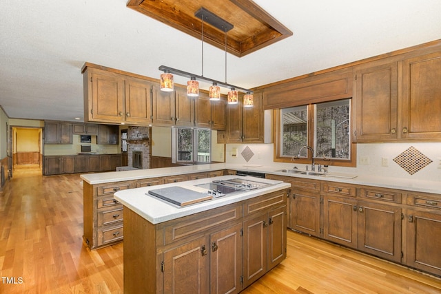 kitchen featuring a center island, light wood finished floors, light countertops, a sink, and a peninsula