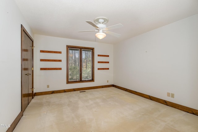 carpeted empty room with ceiling fan, visible vents, and baseboards