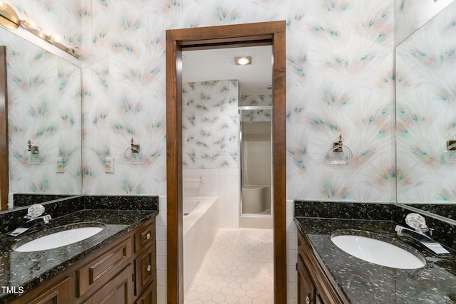 full bathroom featuring a shower stall, two vanities, a sink, and wallpapered walls