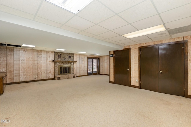 below grade area with a brick fireplace, carpet flooring, and a paneled ceiling