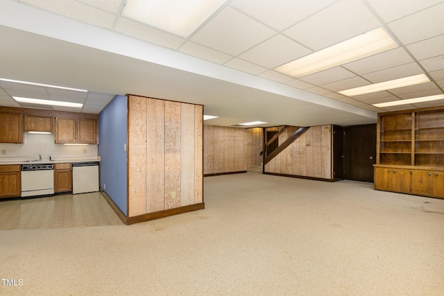 interior space with open floor plan, a drop ceiling, brown cabinetry, and white dishwasher