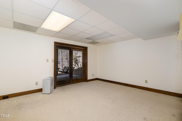 unfurnished room with carpet floors, baseboards, and a drop ceiling