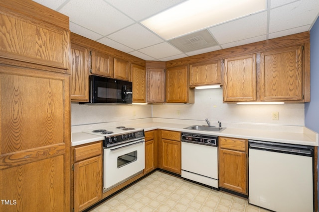 kitchen with white appliances, visible vents, light countertops, light floors, and a sink