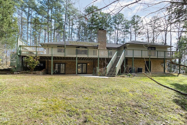 rear view of property featuring a deck, a chimney, a yard, and stairway