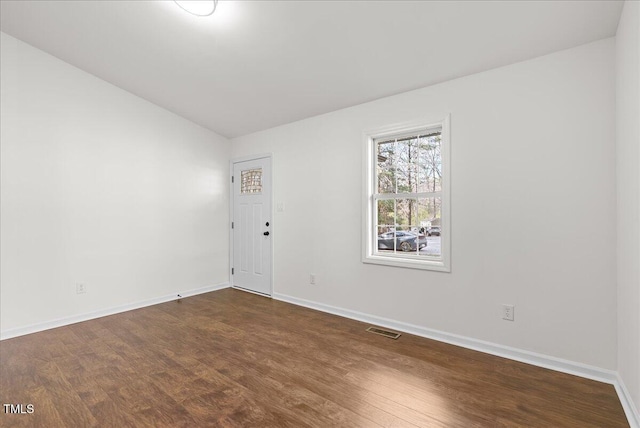 spare room featuring dark wood finished floors, visible vents, and baseboards