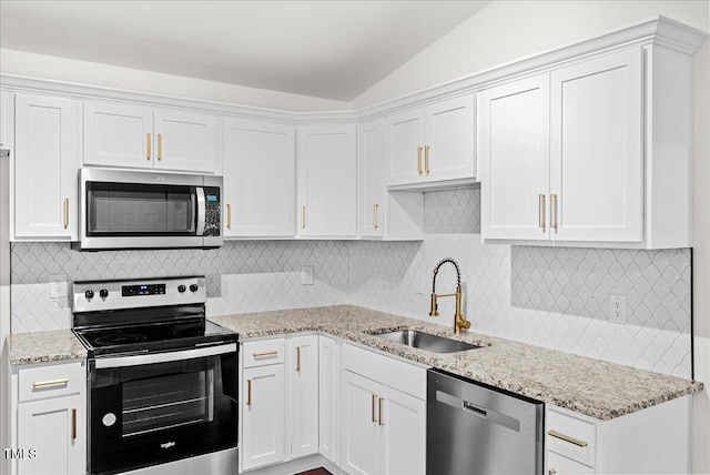 kitchen featuring light stone counters, a sink, white cabinets, vaulted ceiling, and appliances with stainless steel finishes