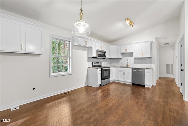 kitchen featuring visible vents, decorative backsplash, vaulted ceiling, stainless steel appliances, and white cabinetry