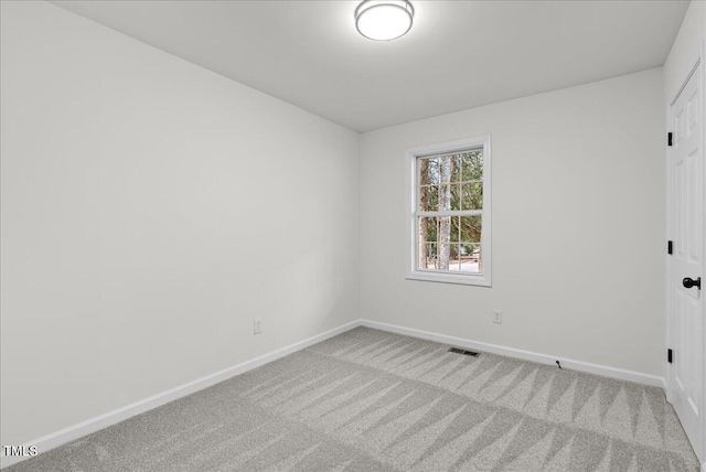 spare room featuring carpet flooring, visible vents, and baseboards