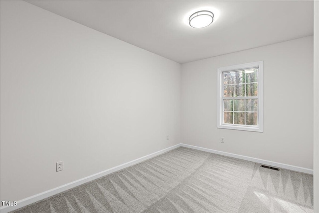 carpeted spare room with visible vents and baseboards