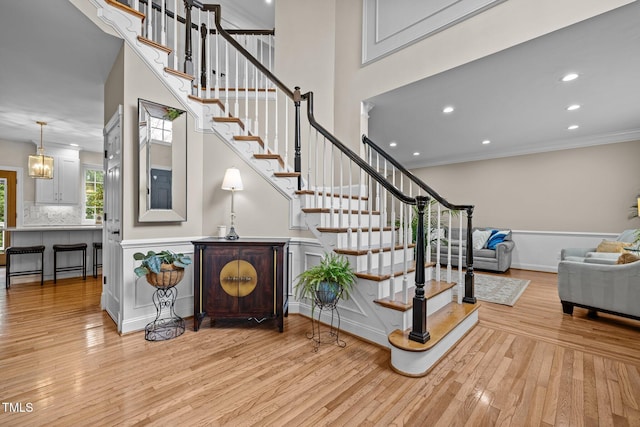 stairs featuring baseboards, a high ceiling, recessed lighting, ornamental molding, and hardwood / wood-style flooring