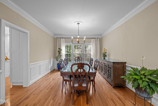 dining area with a chandelier, crown molding, and light wood-style floors