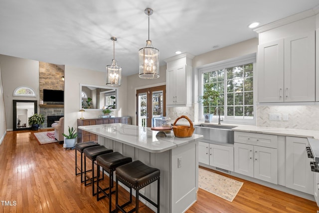 kitchen featuring a healthy amount of sunlight, light wood finished floors, a kitchen island, a breakfast bar, and decorative backsplash