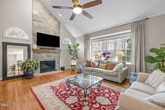 living area featuring a fireplace, high vaulted ceiling, ceiling fan, and wood finished floors