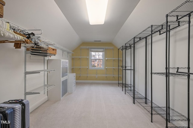 spacious closet with vaulted ceiling and light colored carpet