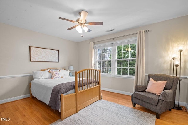 bedroom with ceiling fan, wood finished floors, visible vents, and baseboards