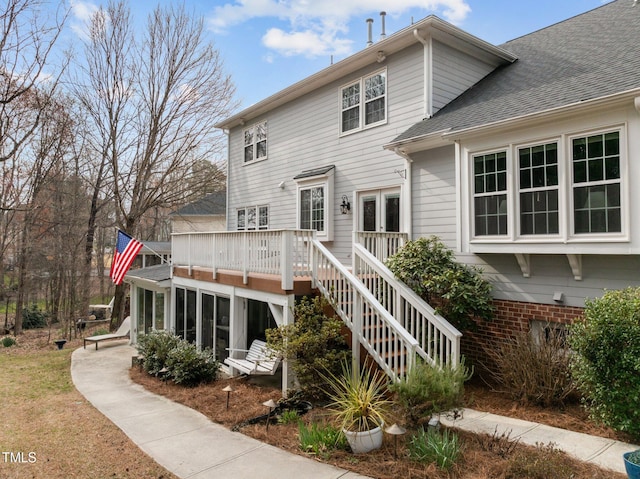 back of house with stairway, a shingled roof, a deck, and a sunroom