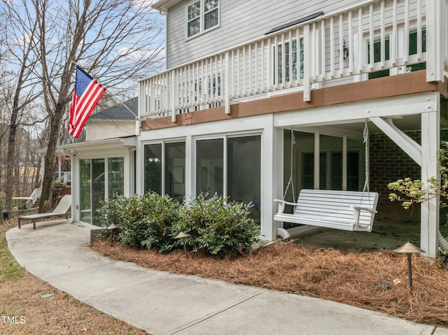 back of property with a balcony and a sunroom