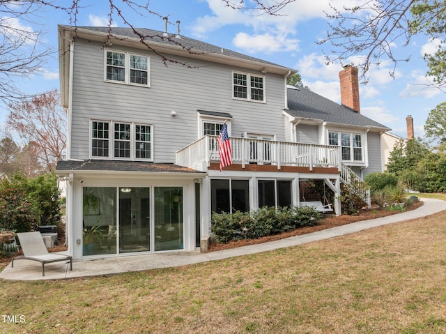 rear view of property featuring a deck, stairs, a yard, a chimney, and a patio area