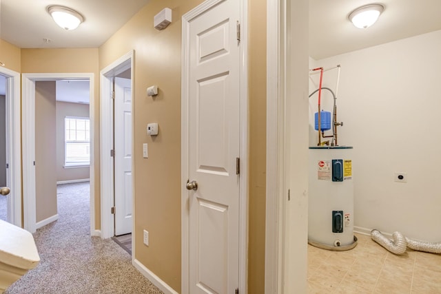 hallway featuring carpet floors, water heater, and baseboards