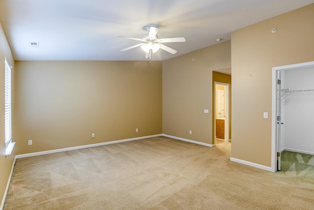 unfurnished bedroom featuring a spacious closet, light carpet, ceiling fan, multiple windows, and baseboards