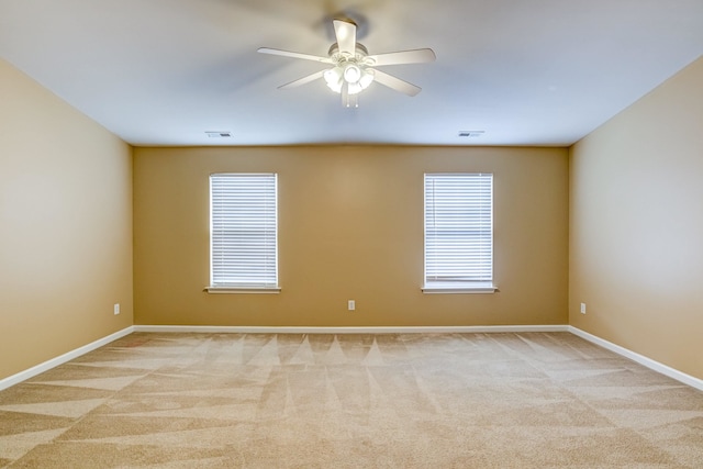 carpeted spare room with a ceiling fan, visible vents, and baseboards