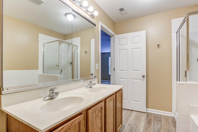 bathroom featuring a stall shower, visible vents, a sink, and wood finished floors