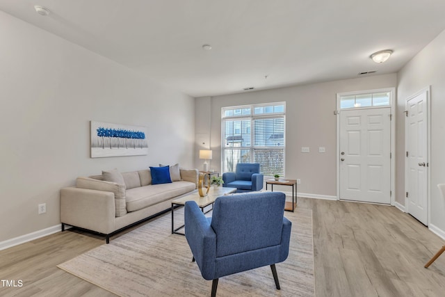 living area featuring baseboards, visible vents, and light wood finished floors