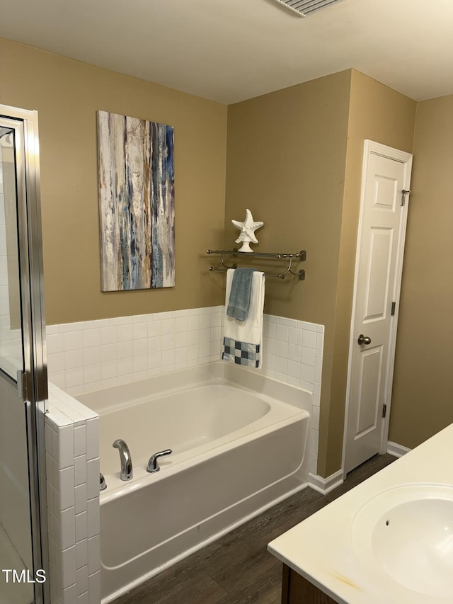 bathroom with wood finished floors, visible vents, vanity, and a bath