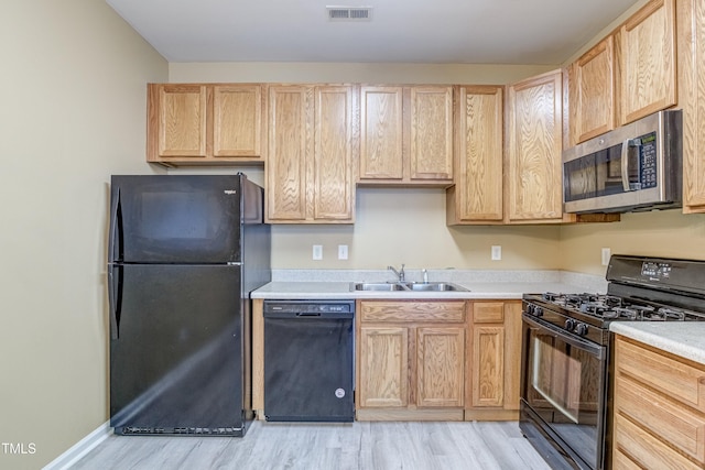 kitchen with black appliances, visible vents, a sink, and light brown cabinetry