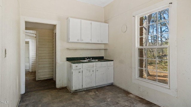 kitchen featuring dark countertops, white cabinets, and a sink