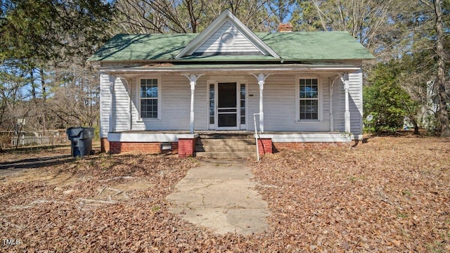 view of front of home with covered porch, crawl space, and a chimney