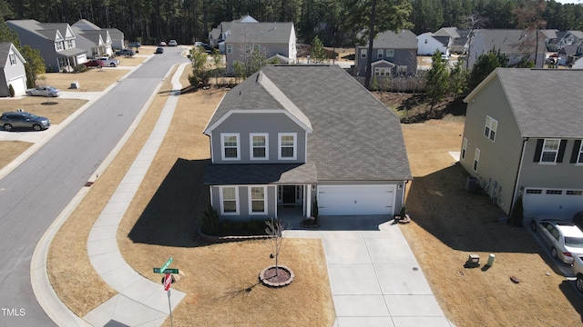 view of front of property with driveway, a garage, a residential view, and roof with shingles