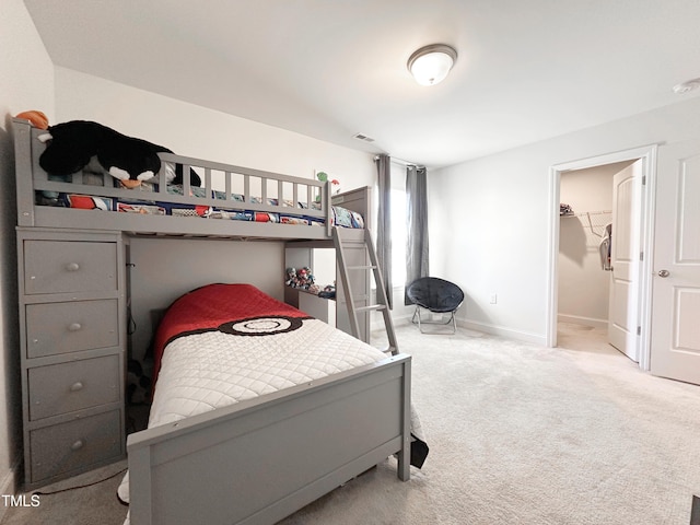 carpeted bedroom with a spacious closet and baseboards