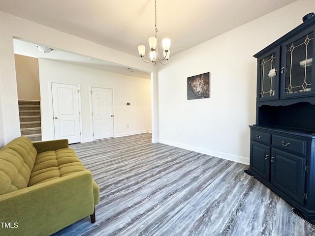 living room with stairs, a notable chandelier, wood finished floors, and baseboards