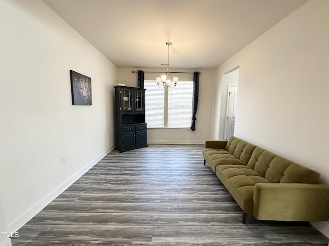 living area featuring baseboards, dark wood-type flooring, and a notable chandelier