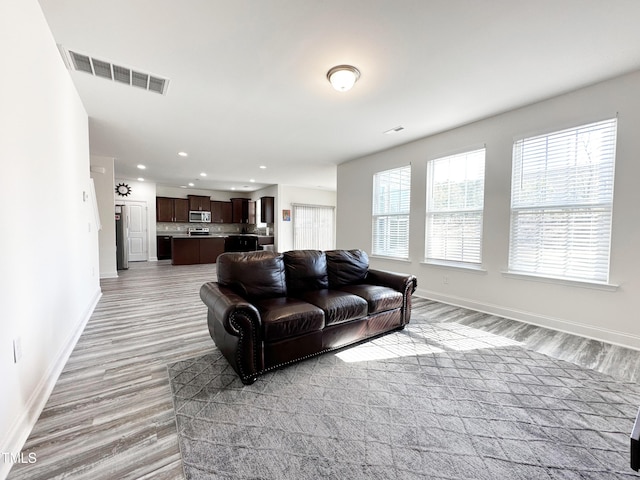 living room with light wood-style floors, baseboards, visible vents, and recessed lighting