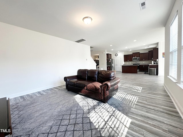 living room with recessed lighting, visible vents, and baseboards