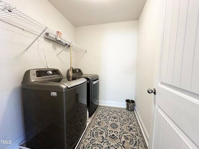 laundry area with tile patterned floors, laundry area, baseboards, and separate washer and dryer