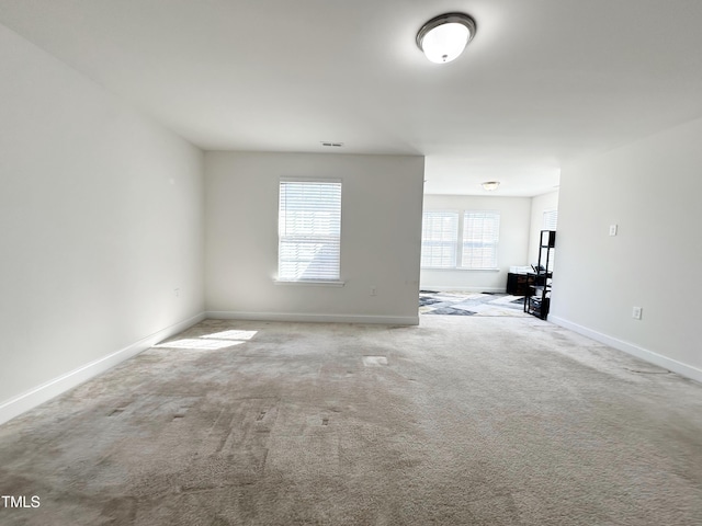 empty room featuring carpet, visible vents, and baseboards