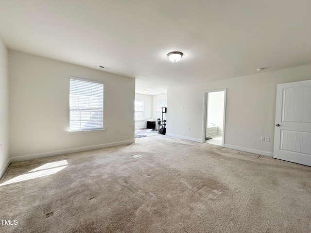 spare room with light carpet, visible vents, and baseboards