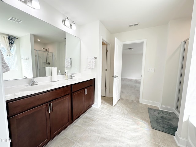 bathroom featuring double vanity, a stall shower, visible vents, and a sink